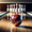 A perfectly aimed bowling ball on its way to strike the pins. The scene is set in a bowling alley with a shiny wooden lane. 